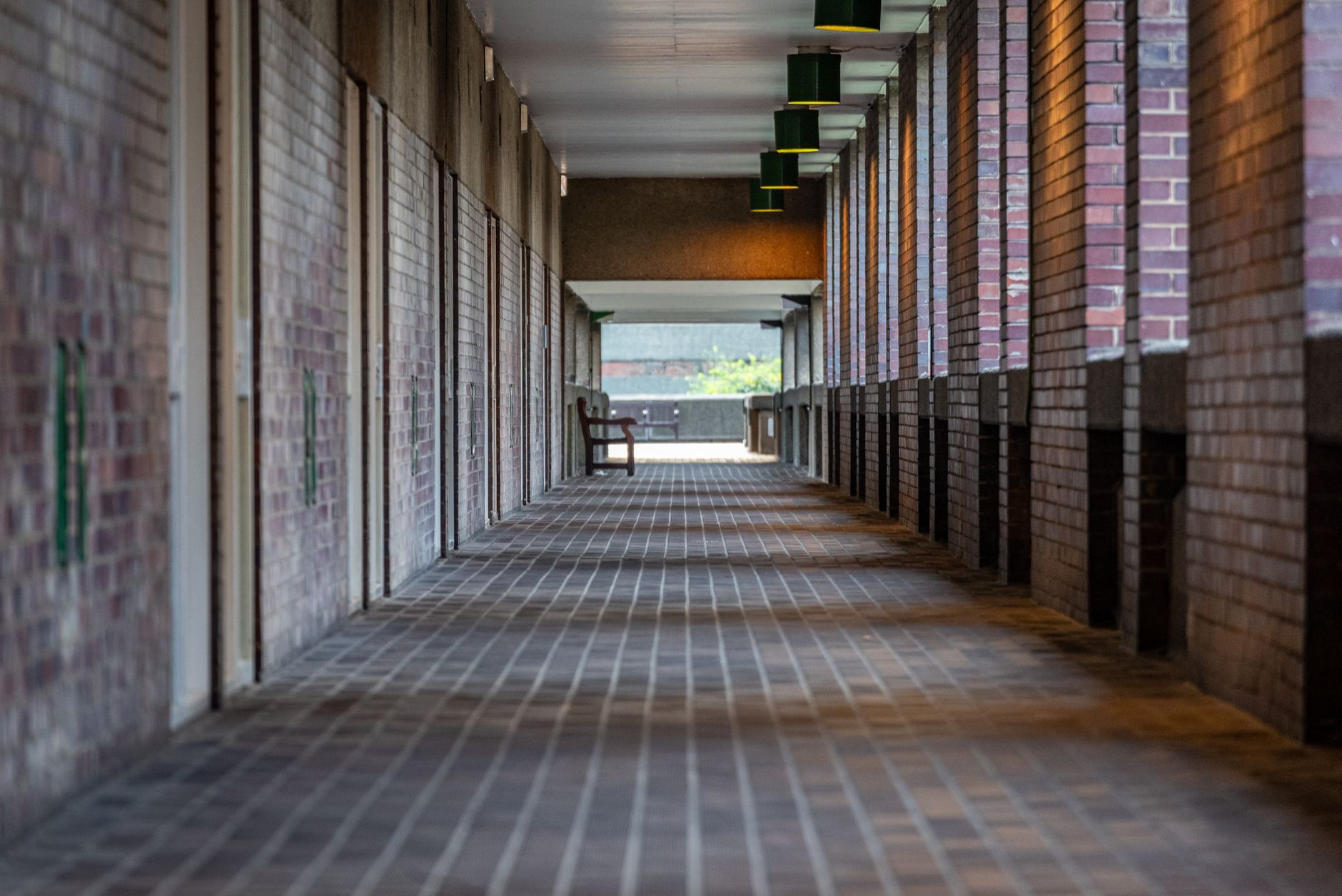 A long data centre corridor between server racks lit by rows of ceiling lights