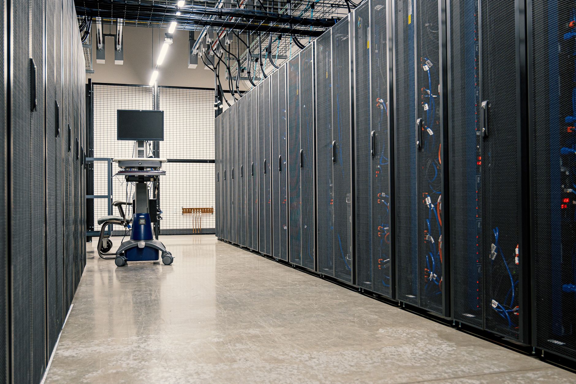 Long aisle between server racks in a dimly lit data center